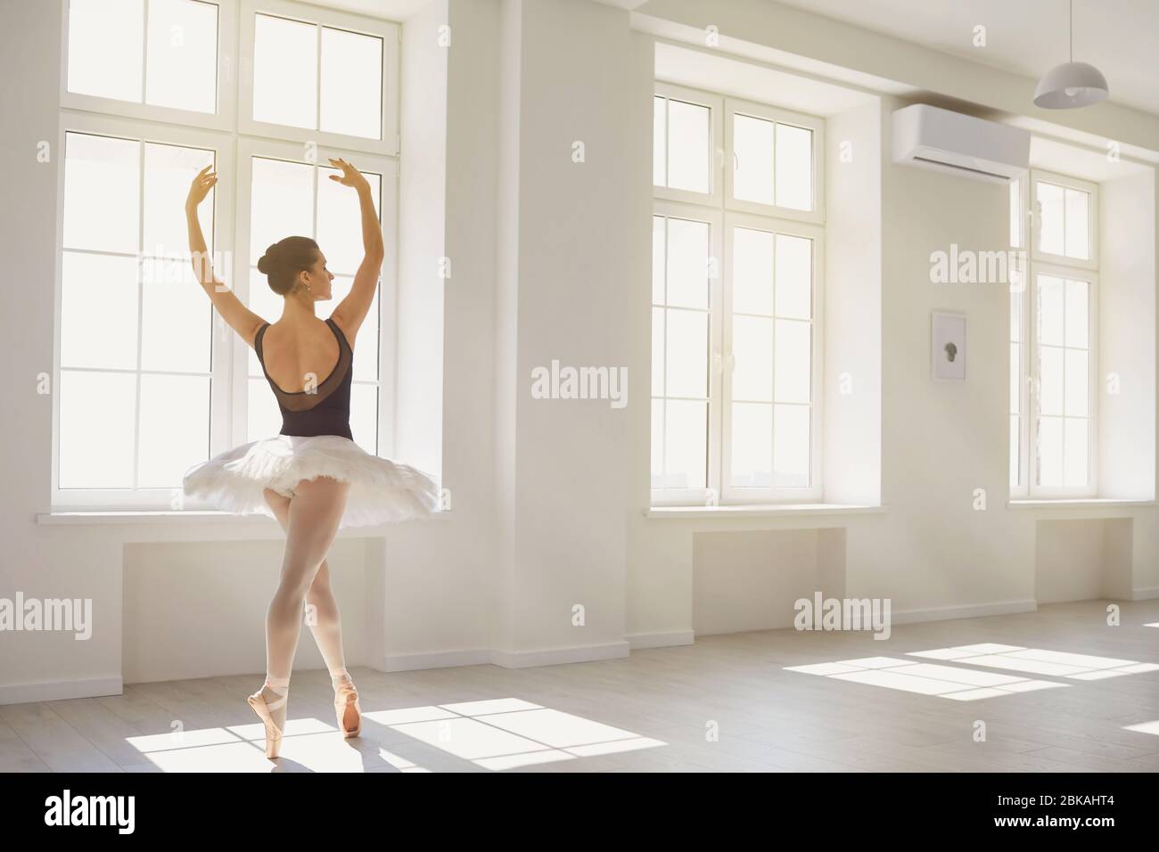 Ballerine. La jeune danseuse de ballet élégante répète une performance dans un studio blanc avec des fenêtres. Banque D'Images