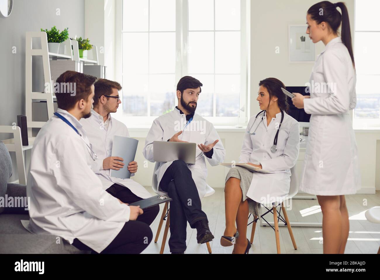 Groupe de médecins praticiens lors d'une réunion discuter du diagnostic d'un patient debout dans un bureau de clinique. Banque D'Images