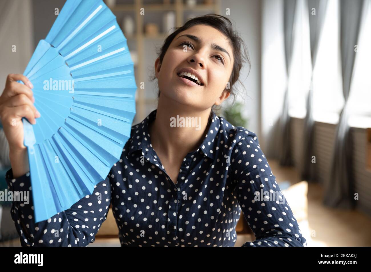 La jeune femme indienne a tiré dessus avec un ventilateur en papier bleu. Banque D'Images