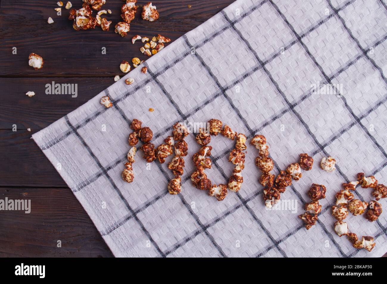 Grains de popcorn au chocolat disposés en mots de cinéma sur fond de serviette blanc. Banque D'Images
