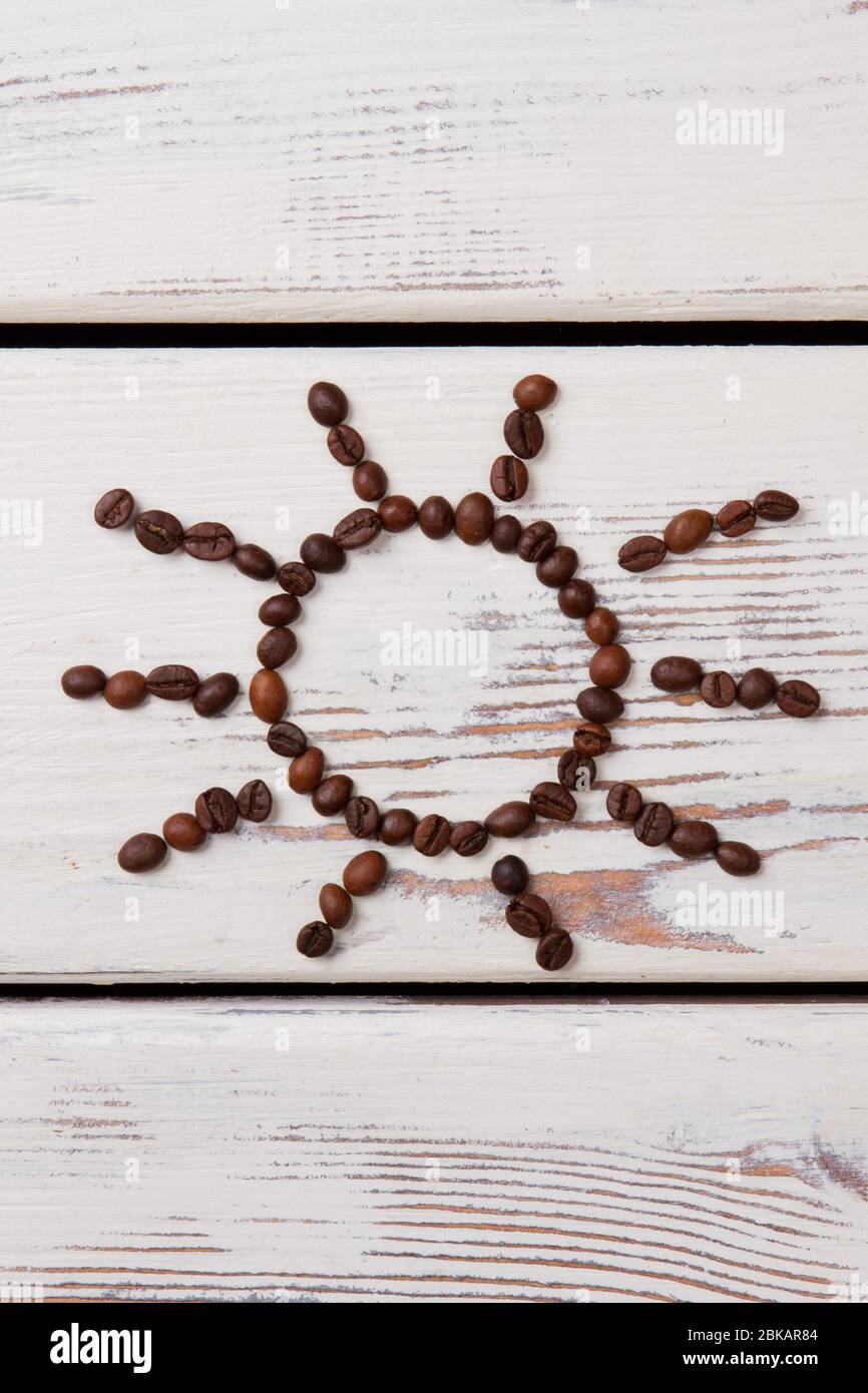 Grains de café rôtis disposés en forme de soleil. Banque D'Images Grains de café rôtis disposés en forme de soleil. Banque D'Images