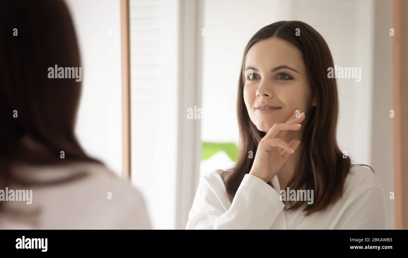 Les jeunes femmes regardent dans le miroir font des procédures faciales Banque D'Images