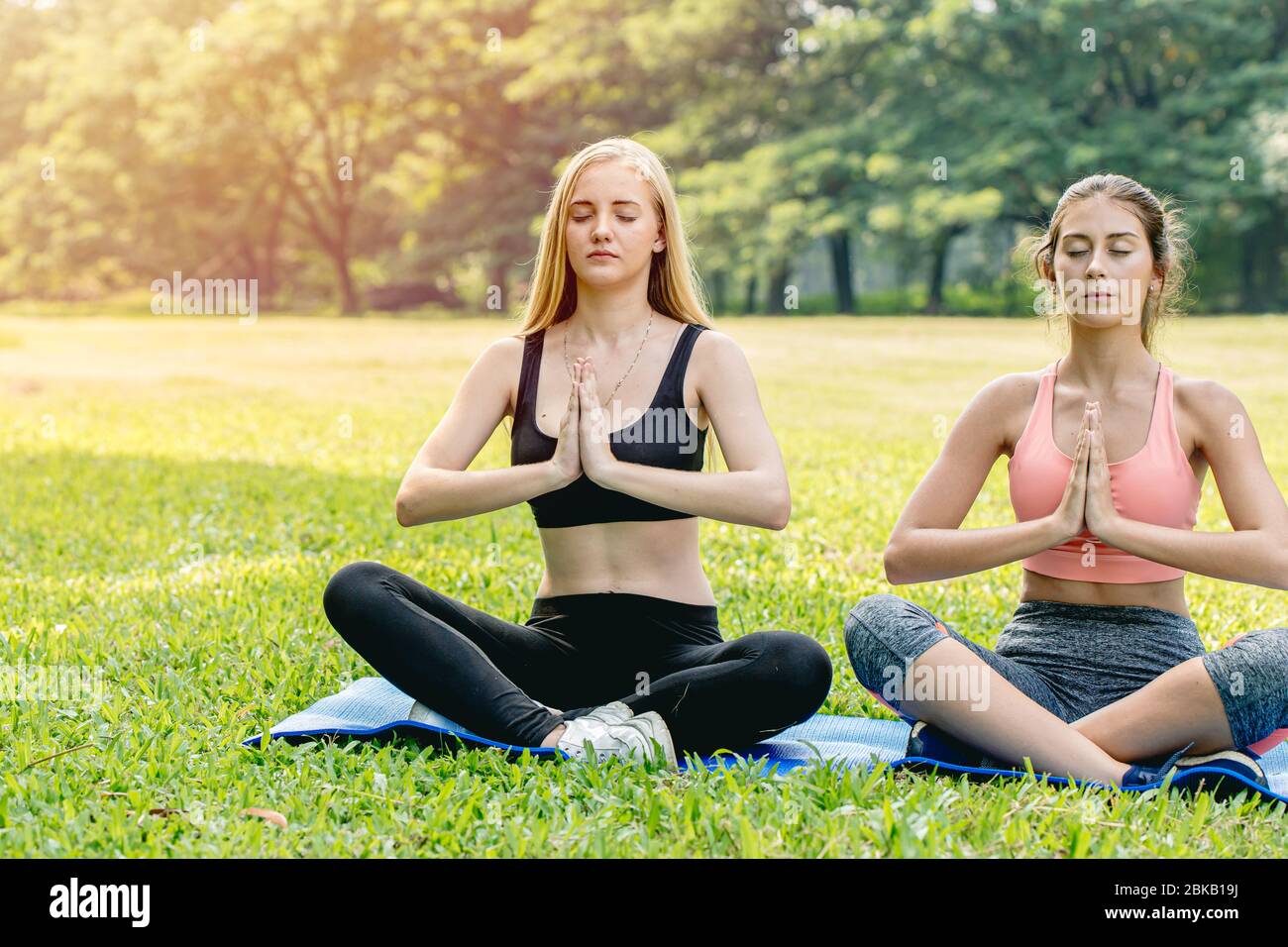 Belles filles adolescence ami faire yoga pour la santé dans le parc vert vacances assis main lotus yeux fermé posture de concentration. Banque D'Images