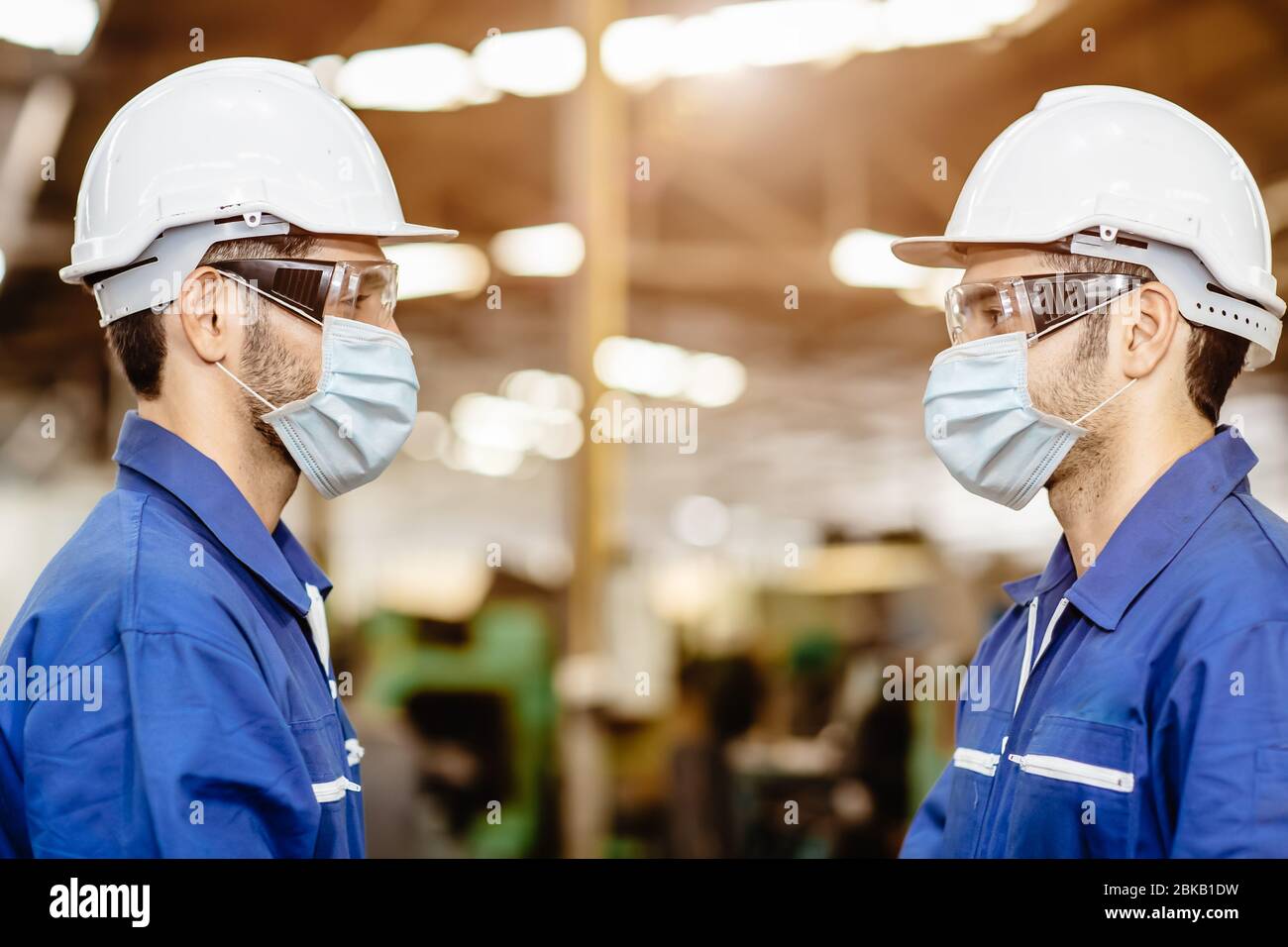 Les travailleurs portent un masque de visage distançant pendant la conversation ensemble service woking en usine pour empêcher Covid-19 virus de la pollution de la poussière d'air et pour le bien Banque D'Images
