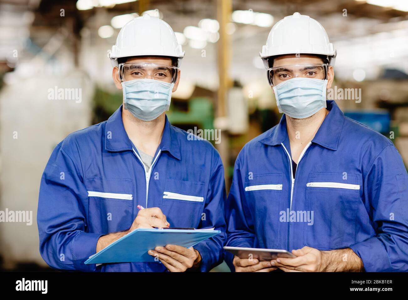 Les hommes de l'industrie portent un masque facial lors de l'entretien en usine pour prévenir la pollution par la poussière d'air du virus Covid-19 et pour une bonne santé. Banque D'Images