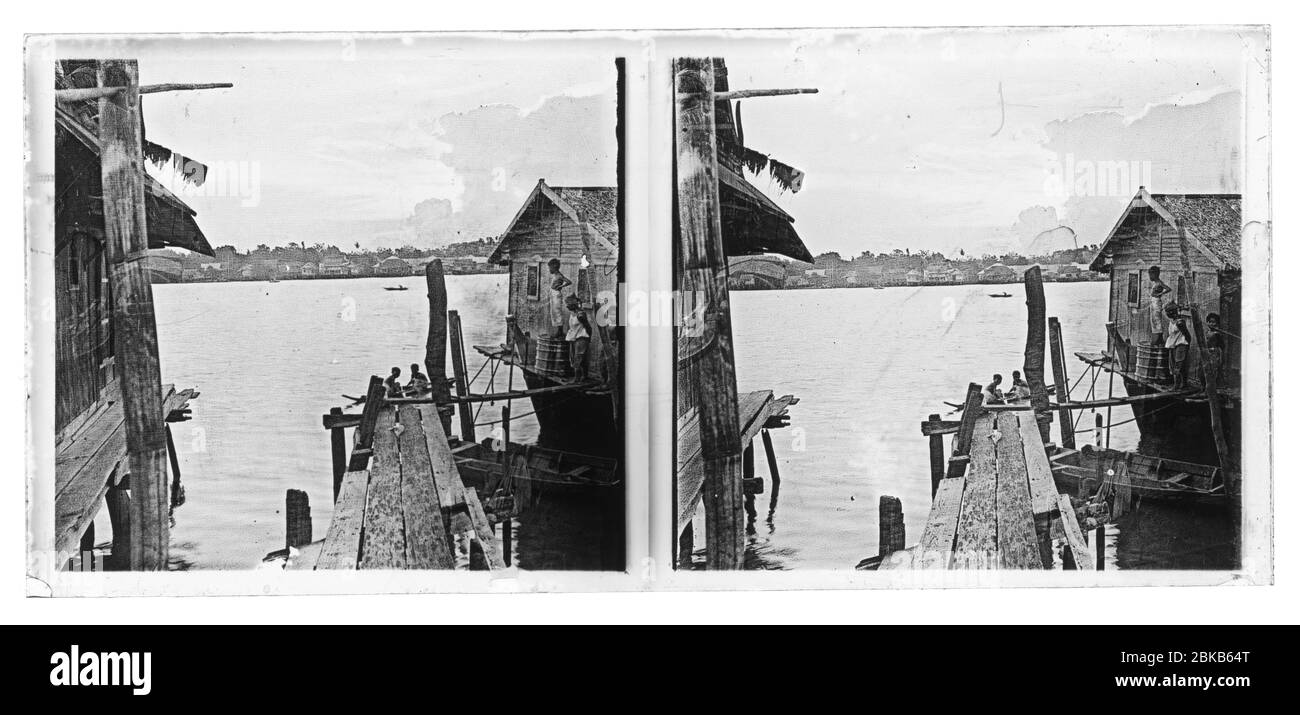 Maisons en bois stilt traditionnelles au bord de l'eau au Cambodge à Mékong ou Tonle SAP. Les enfants qui se tiennent à la maison en regardant leurs copains pagayer dans un bateau traditionnel sur la rivière. Photo stéréo d'environ 1910. Photo sur la plaque de verre sèche de la collection Herry W. Schaefer Banque D'Images