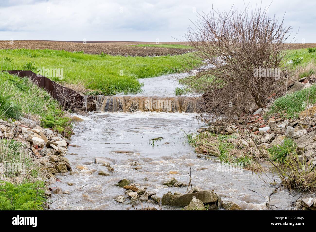 L'eau qui coule dans la voie navigable du champ agricole après de fortes pluies et des tempêtes ont causé des inondations. Concept d'érosion du sol, de contrôle et de gestion du ruissellement des eaux Banque D'Images