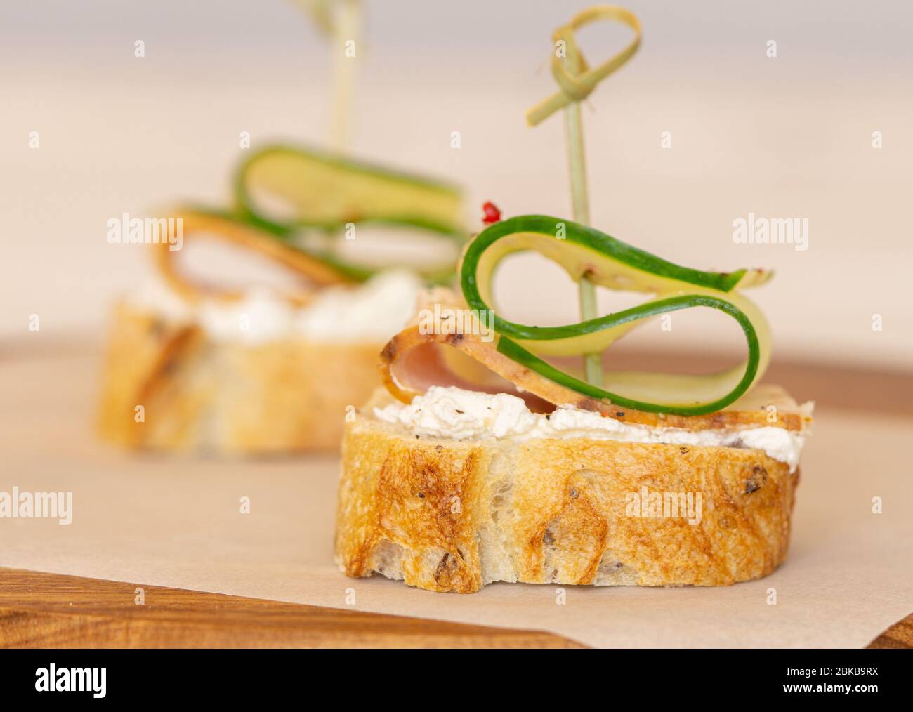 Petits sandwiches au jambon concombre avec fromage doux sur une table en bois. Banque D'Images