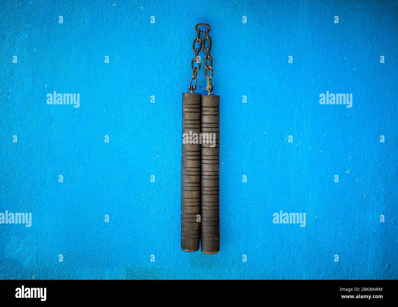 Arme Nunchaku isolée sur fond bleu. Formation nunchaku noir pour débutant. Équipement d'arts martiaux Hot Tactical Gear. Banque D'Images