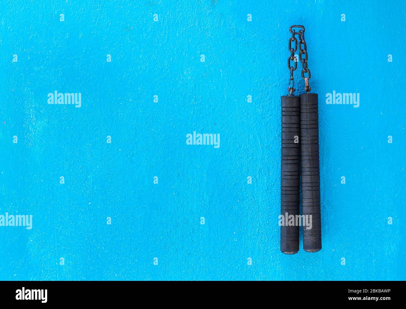 Arme Nunchaku isolée sur fond bleu. Formation nunchaku noir pour débutant. Équipement d'arts martiaux Hot Tactical Gear. Banque D'Images