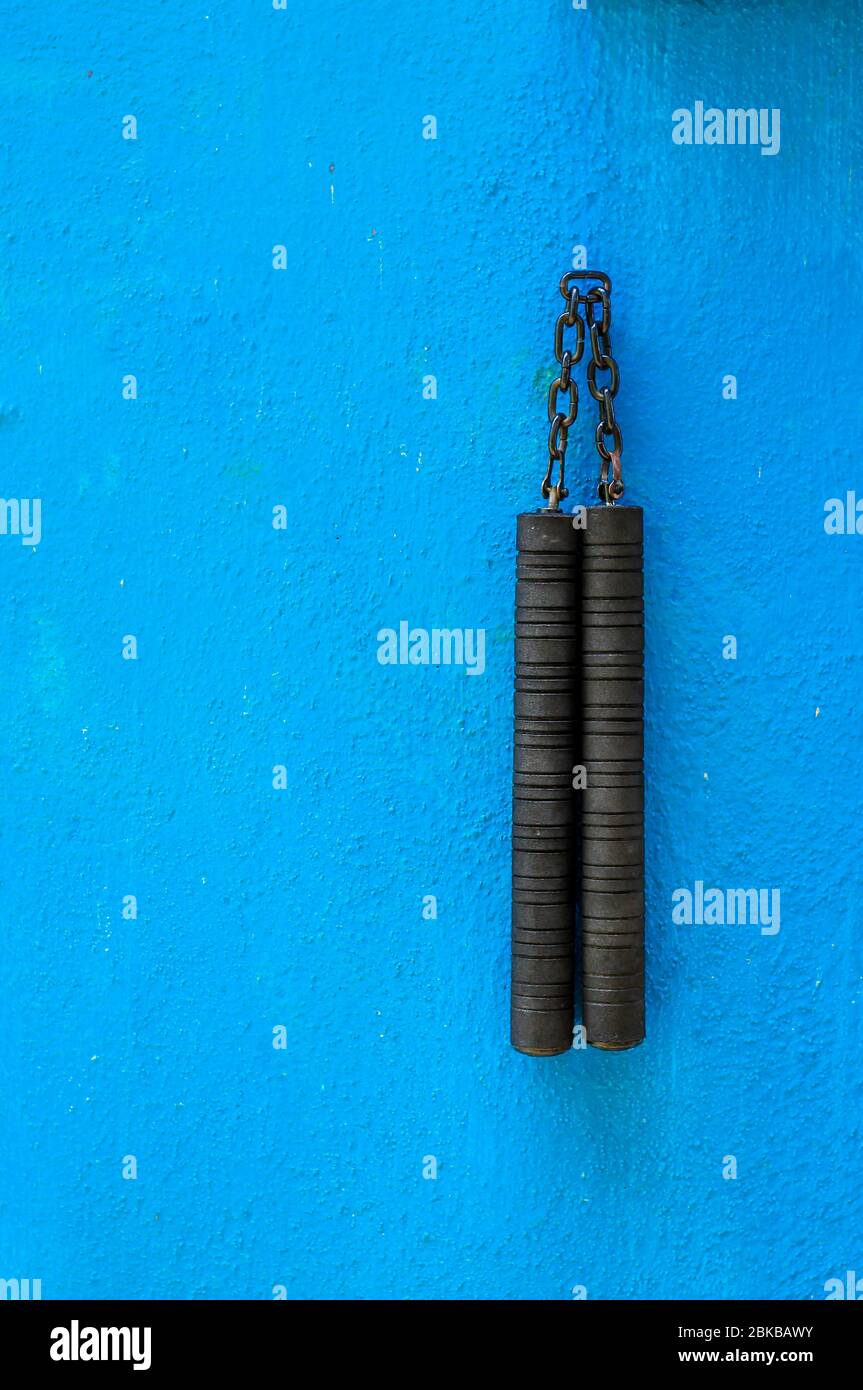 Arme Nunchaku isolée sur fond bleu. Formation nunchaku noir pour débutant. Équipement d'arts martiaux Hot Tactical Gear. Banque D'Images