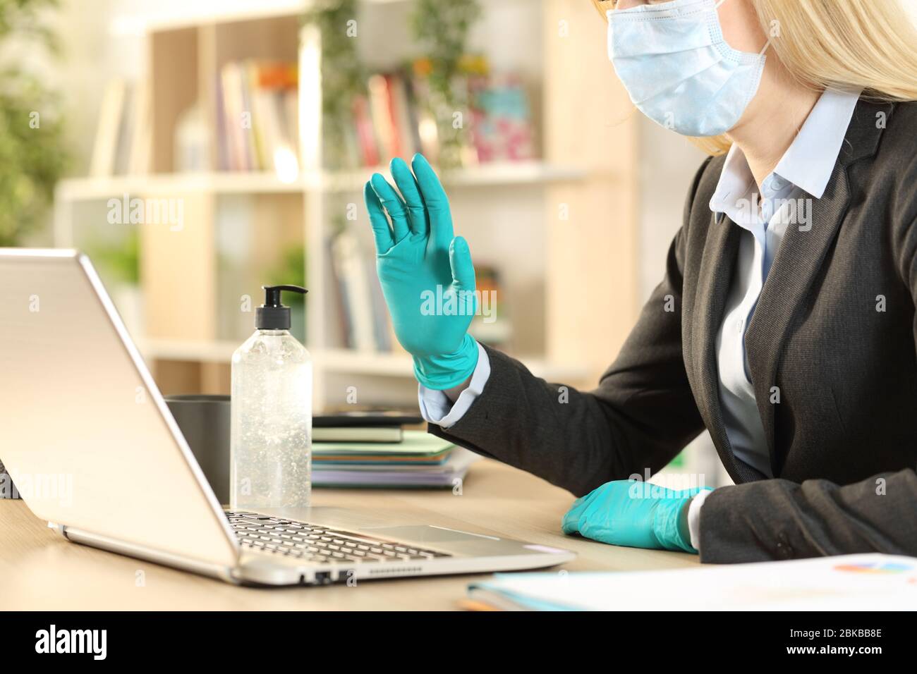 Gros plan femme entrepreneur mains salutation sur videocall sur ordinateur portable éviter le coronavirus avec masque et gants à la maison Banque D'Images