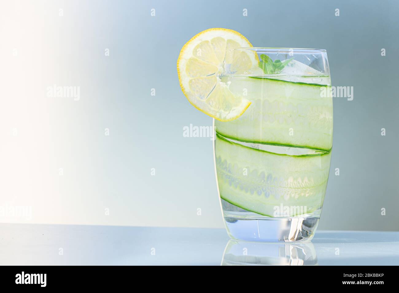 Verre d'eau avec citron isolé sur fond bleu, espace de copie. Banque D'Images