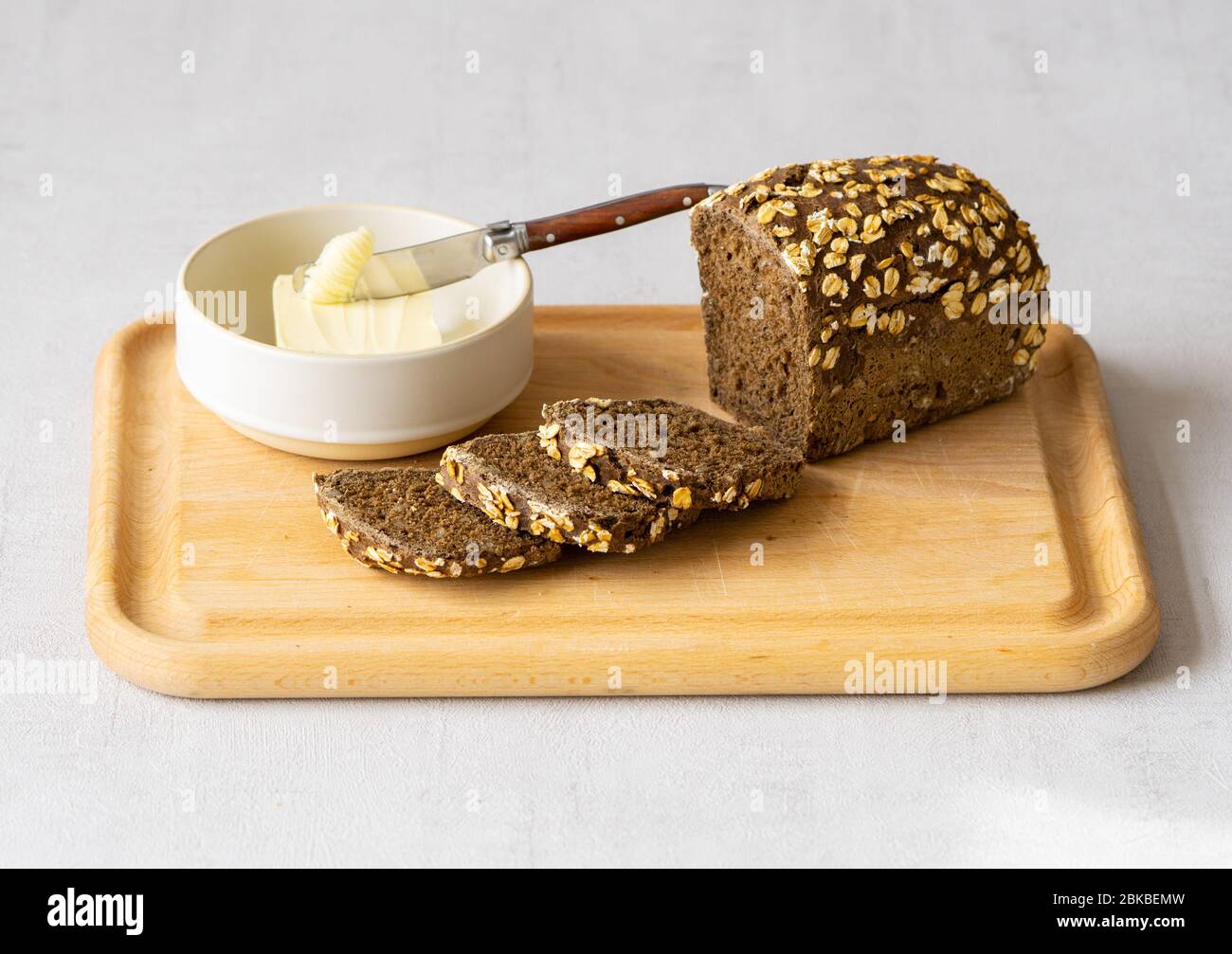 Pain et beurre de grain entier foncé sur planche à découper. Petit déjeuner sain. Banque D'Images