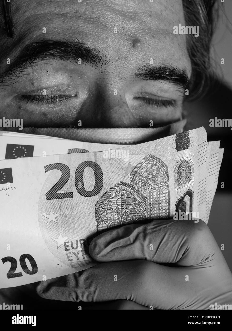 Une main portant des gants de protection bleus tenant des billets en euros - 20 ou 50 - . Coronavirus : plus de protection financière de l'UE et des États-Unis Banque D'Images