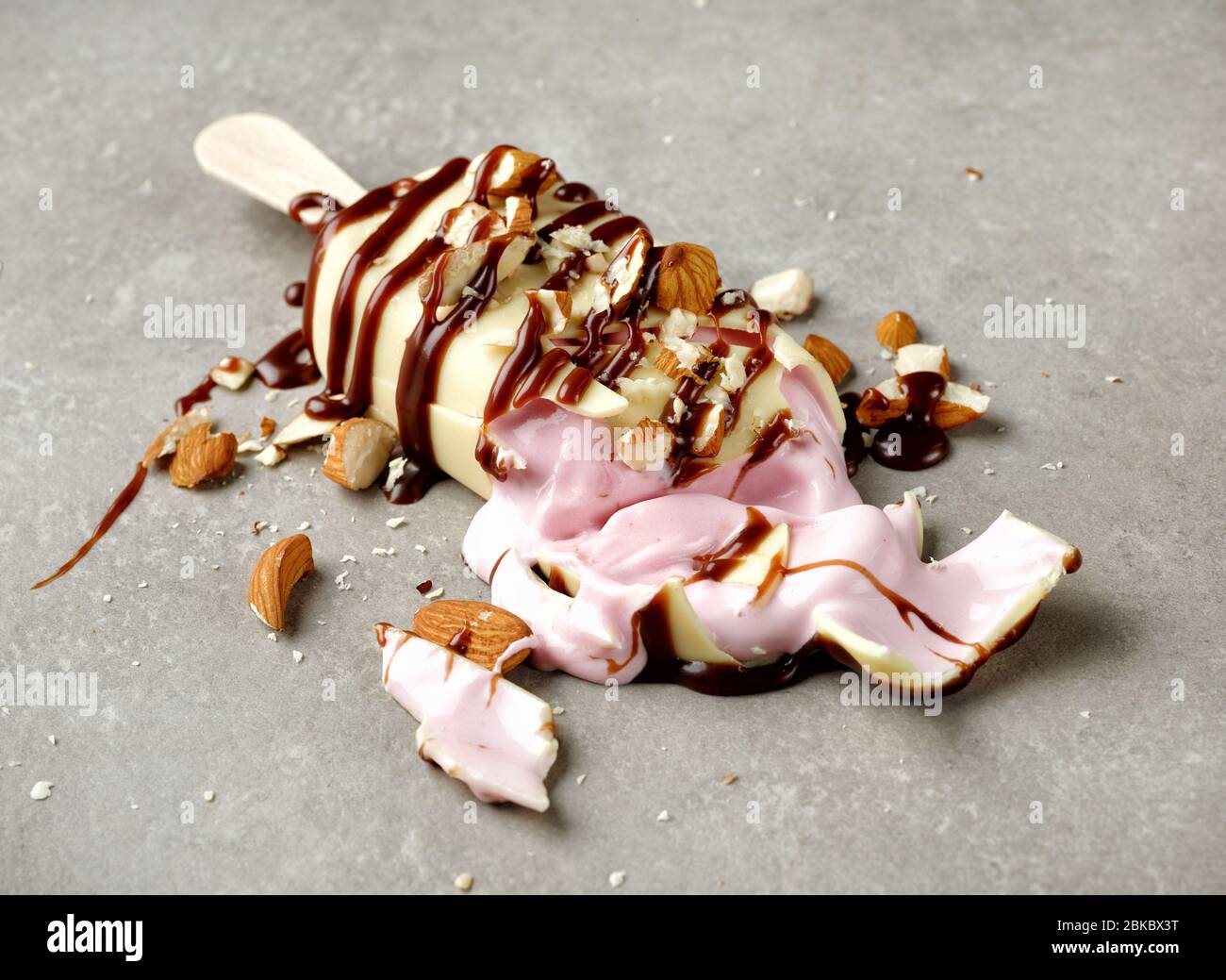 glace brisée recouverte de chocolat blanc décoré de chocolat et d'amandes sur fond gris Banque D'Images