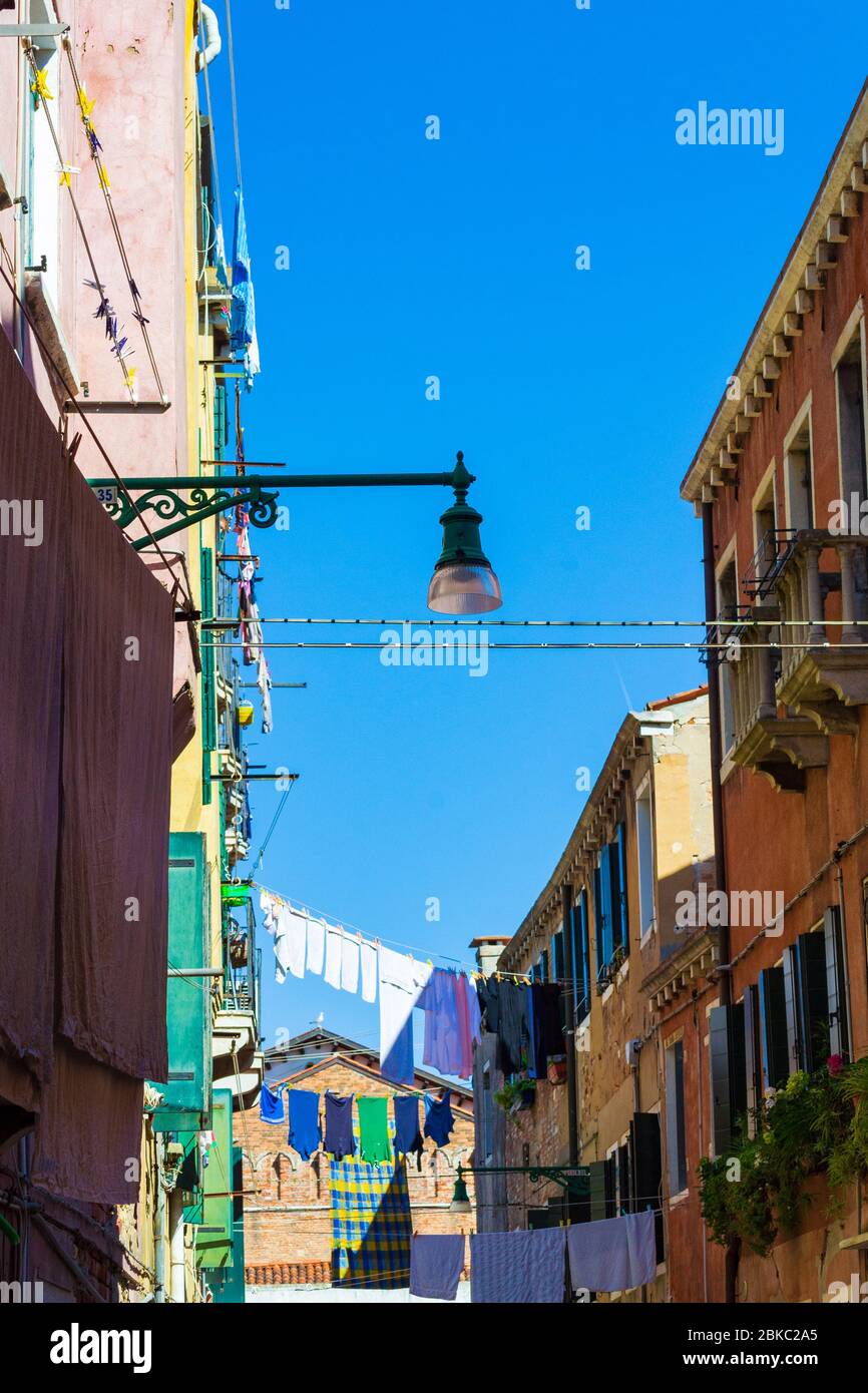 Vêtements lavés sécher dehors sur une corde étirée entre les vieilles maisons historiques au-dessus de la rue étroite, Venise, Vénétie, Italie Banque D'Images