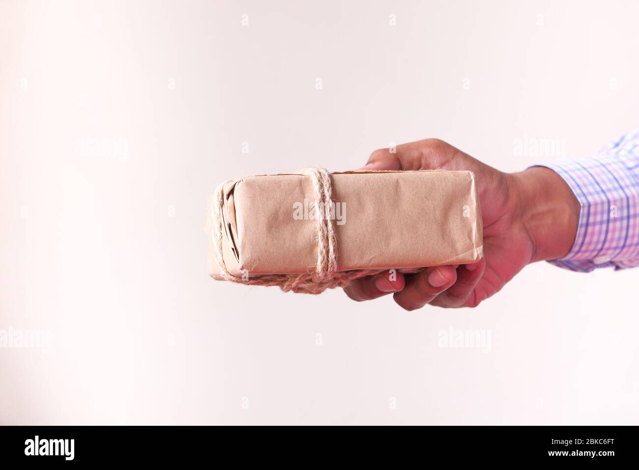 main homme tenant la boîte cadeau contre le mur. Banque D'Images