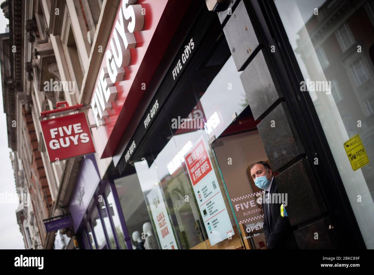 Un homme de sécurité à la porte de cinq gars restaurant à Kensington, Londres, après la chaîne de hamburgers a rouvert huit de leurs sites, comme le Royaume-Uni continue à se verrouiller pour aider à freiner la propagation du coronavirus. Banque D'Images