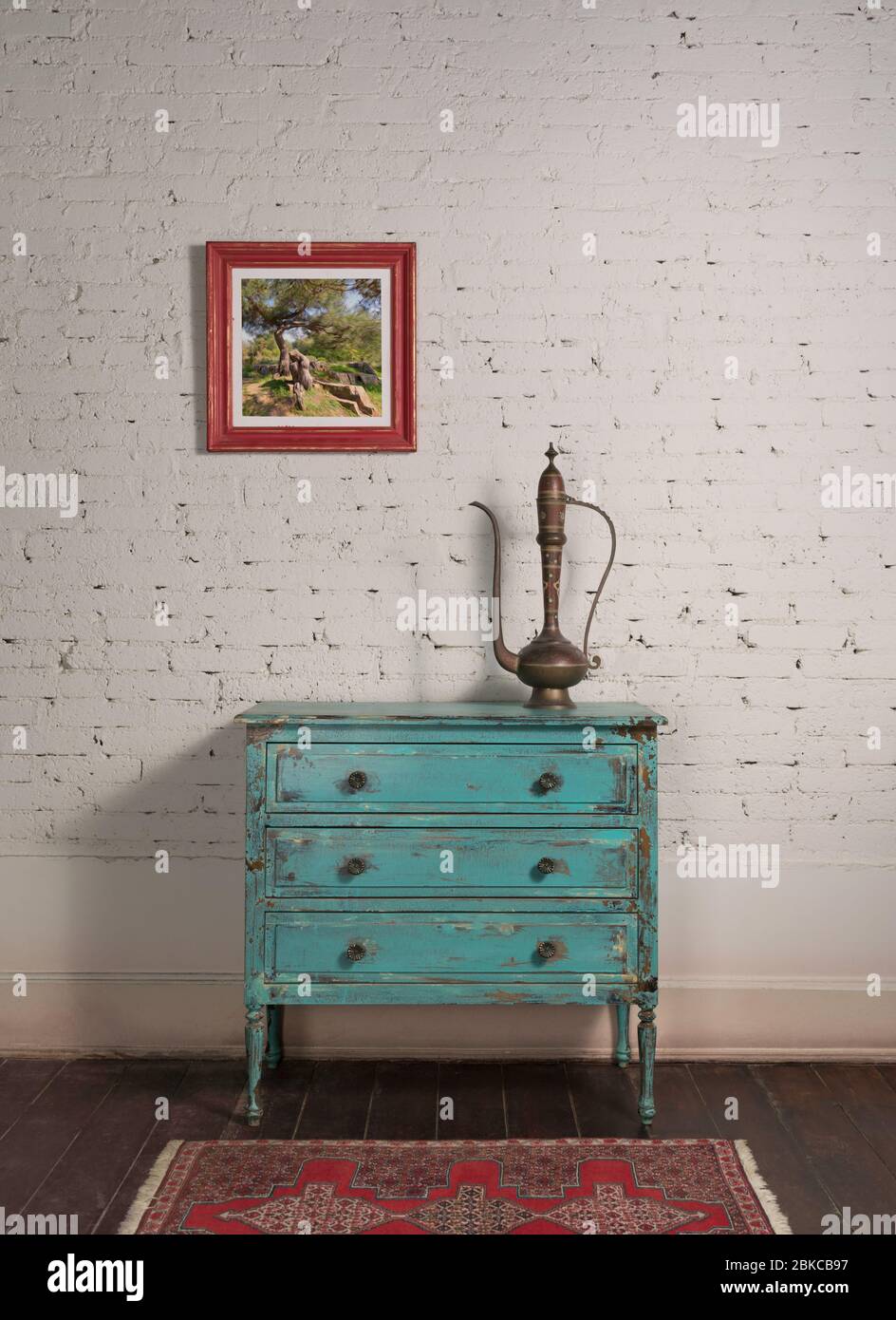 Mur de briques blanches avec théière en cuivre antique sur le dessus de l'élégant cabinet turquoise vintage et peinture pendu dans le salon Banque D'Images