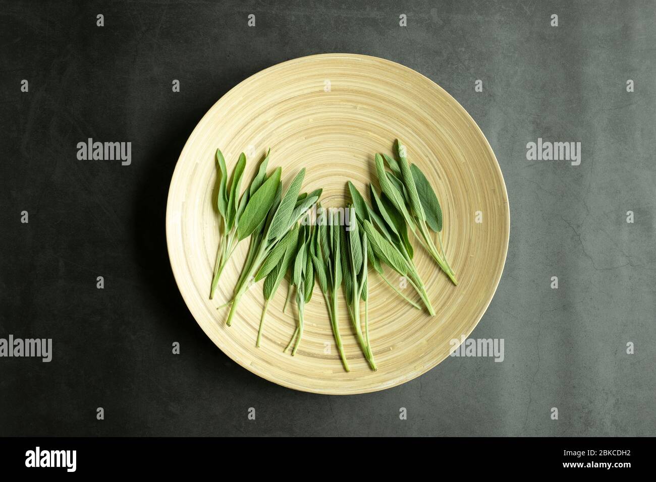 Feuilles de sauge fraîches sur une assiette en bois. Tisane fraîche et biologique. Vue de dessus, dessus, plat. Banque D'Images