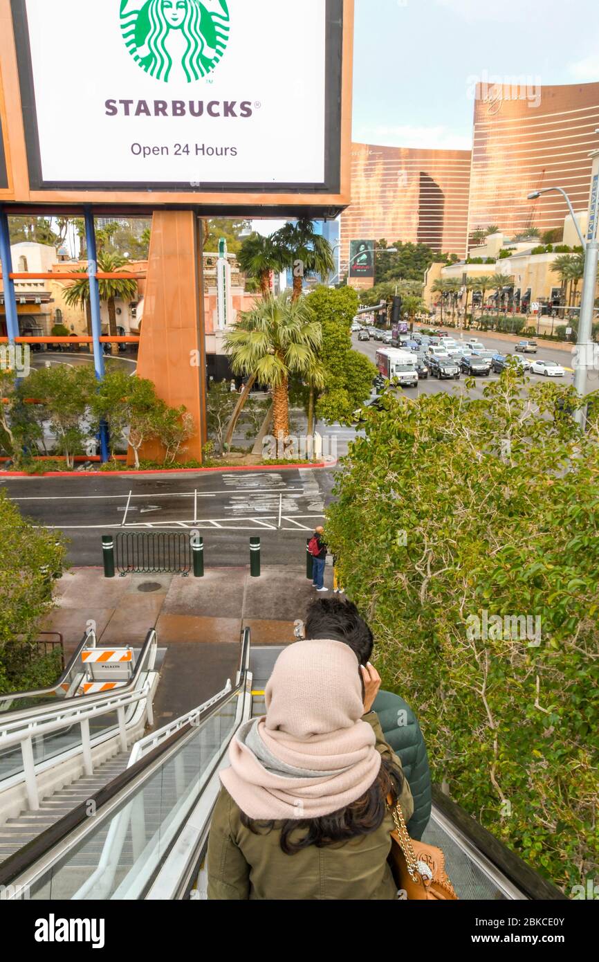 LAS VEGAS, NEVADA, États-Unis - FÉVRIER 2019: Les gens qui descendent un escalier roulant sur Las Vegas Boulevard, avec un panneau électronique faisant de la publicité Starbucks Banque D'Images