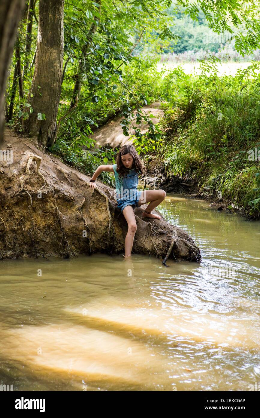 Jeune fille jouant dans un ruisseau boisé à Wowo's, un camping familial à Sussex Banque D'Images