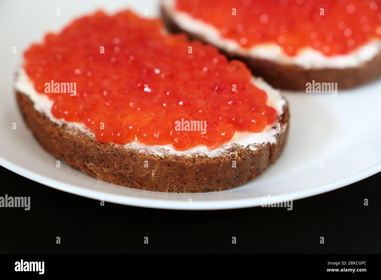 Sandwichs avec caviar rouge, beurre et pain de seigle sur plaque blanche, sélection. Plat russe traditionnel Banque D'Images