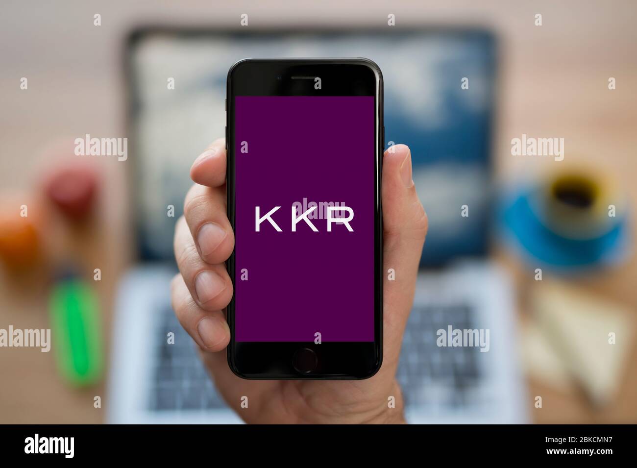 Un homme regarde son iPhone qui affiche le logo KKR (usage éditorial uniquement). Banque D'Images Un homme regarde son iPhone qui affiche le logo KKR (usage éditorial uniquement). Banque D'Images
