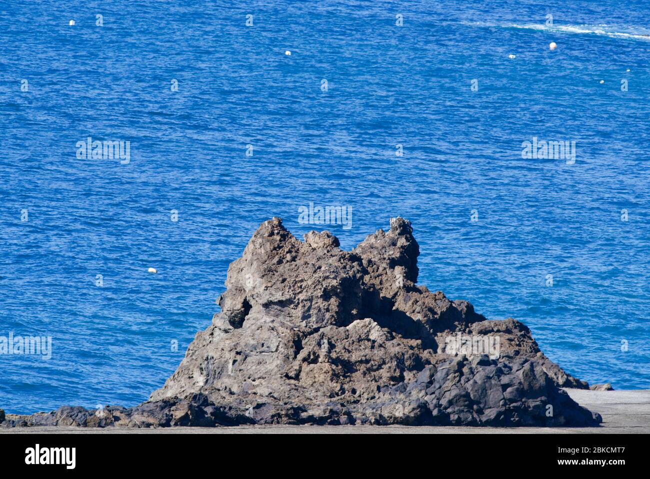 La roche de lave noire, l'océan bleu dans l'océan Banque D'Images