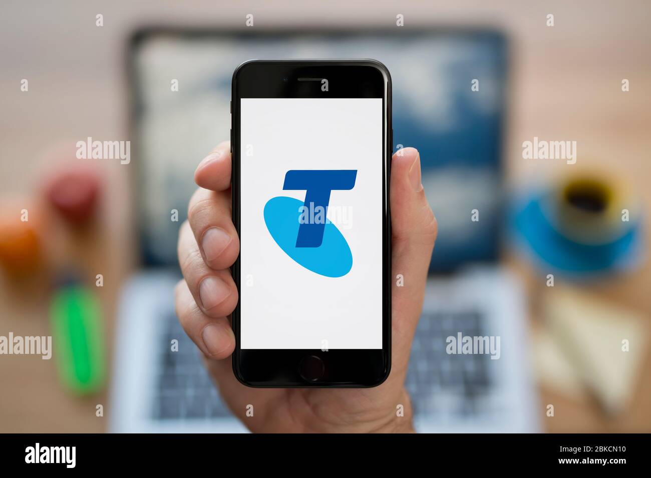 Un homme regarde son iPhone qui affiche le logo Telstra (usage éditorial uniquement). Banque D'Images Un homme regarde son iPhone qui affiche le logo Telstra (usage éditorial uniquement). Banque D'Images