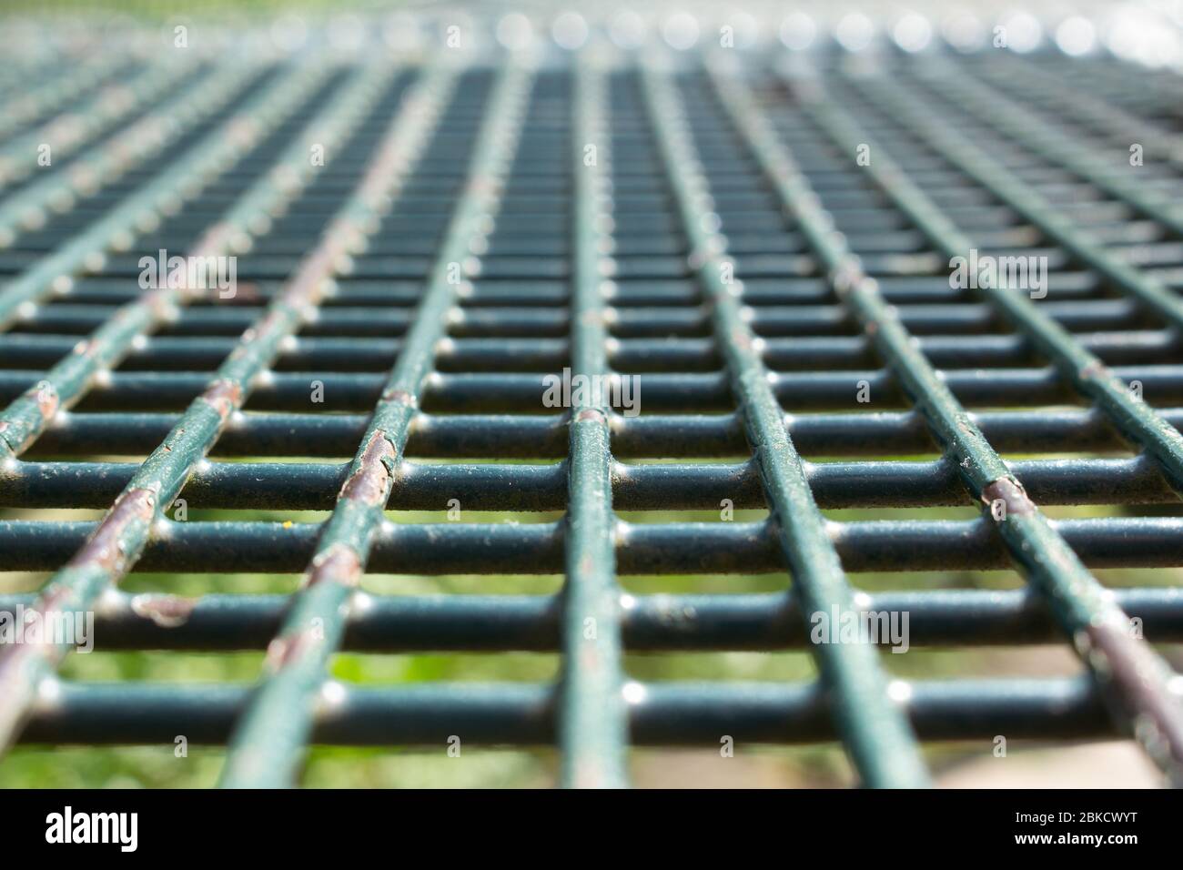 Vue inclinée d'une grille de paillasse de parc en métal vert avec décollement de la peinture, mise au point sélectionnée Banque D'Images