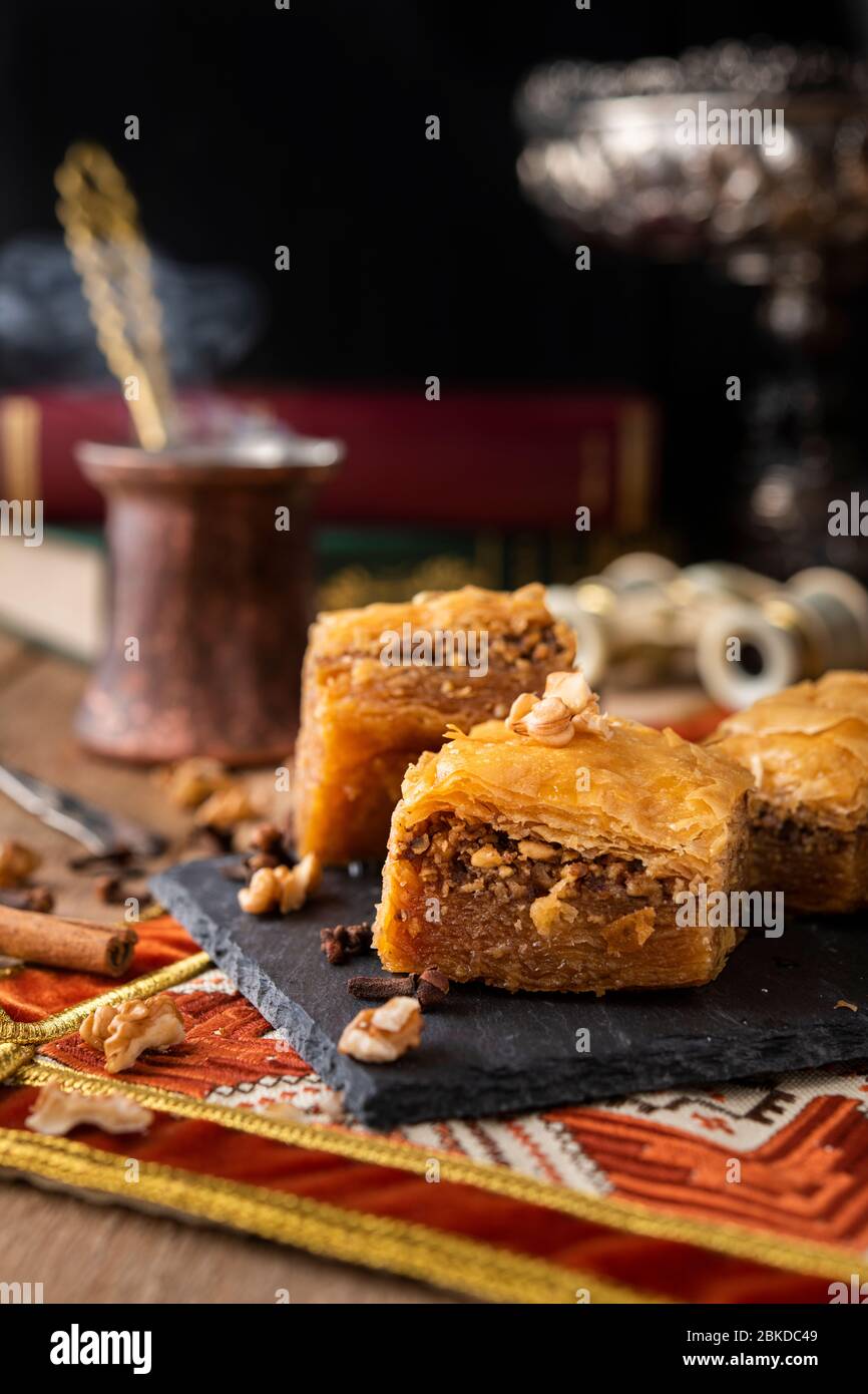 Bonbons baklava sur une pierre noire avec café et livres, jumelles à l'arrière Banque D'Images