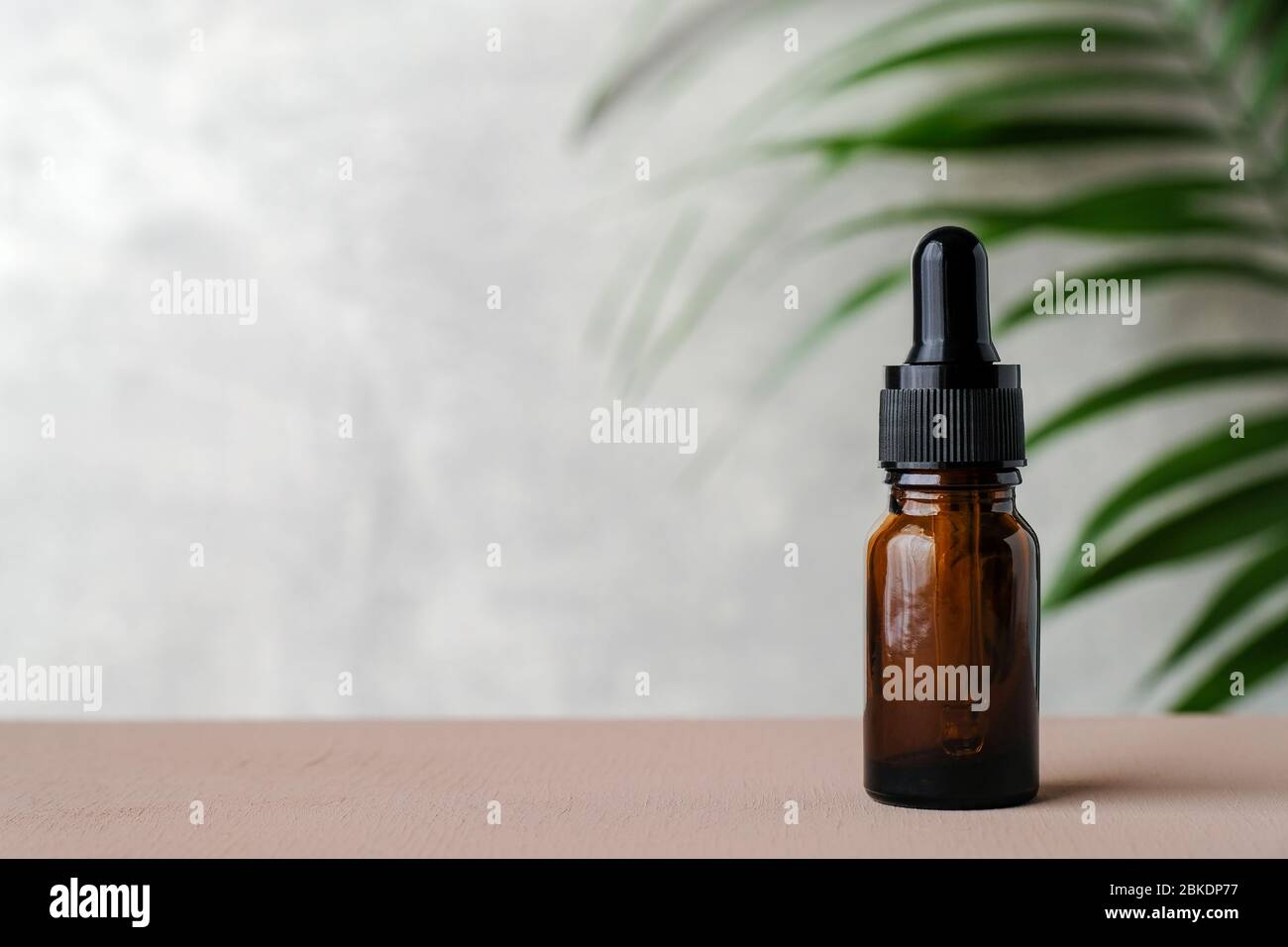 Flacon compte-gouttes. Bouteille de verre ambré foncé avec huile essentielle et feuille tropicale. Cosmétique biologique naturelle, huile de message d'aromathérapie. Banque D'Images