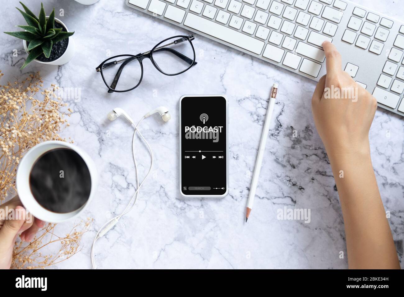concept de contenu audio podcast. application podcast sur écran de smartphone mobile sur bureau avec tasse à café, écouteurs, lunettes, clavier d'ordinateur Banque D'Images