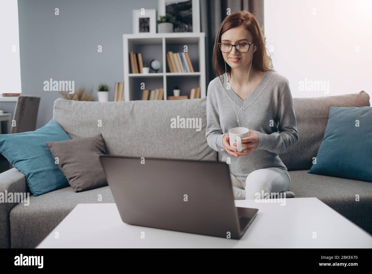 Femme dans un écouteur ayant une conférence en ligne sur ordinateur portable Banque D'Images