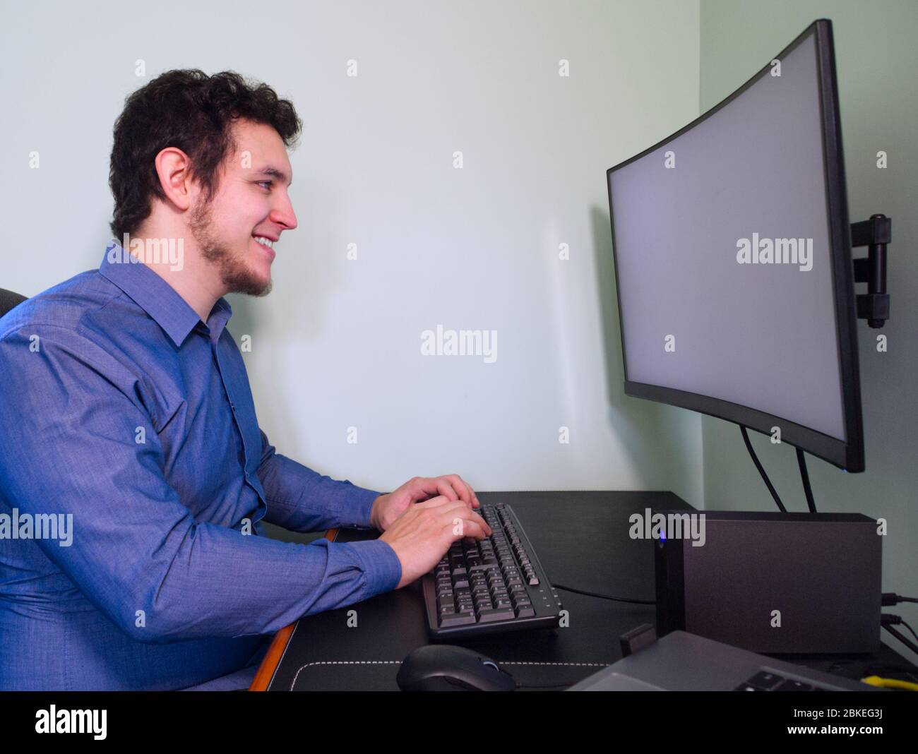 Jeune homme de programmation caucasien riant devant l'ordinateur. Concept de télétravail. Quarantaine. Banque D'Images
