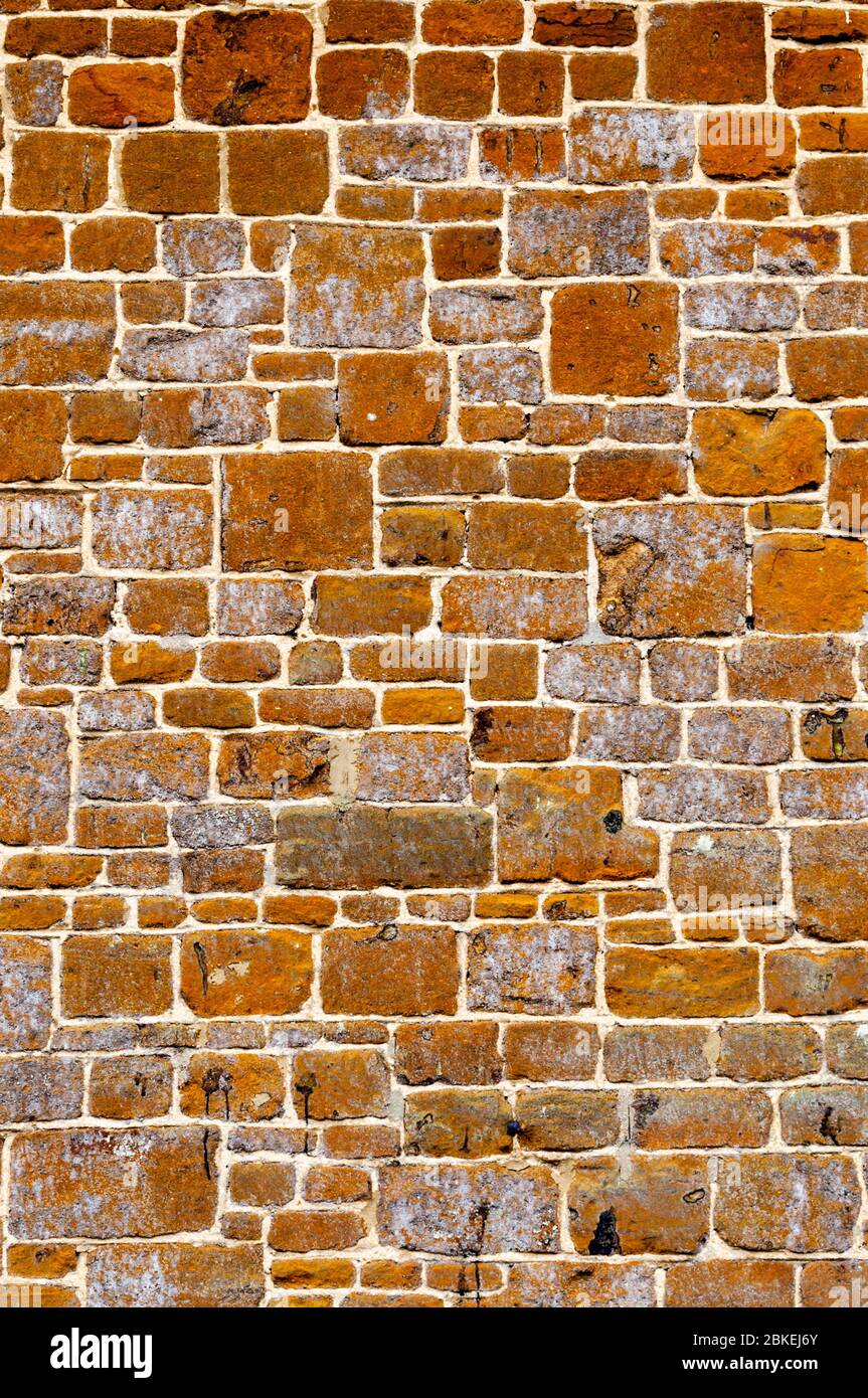 Couper des blocs de pierre à carstone ou de pierre à carrstone utilisés comme matériau de construction dans le côté d'un cottage Norfolk. Banque D'Images