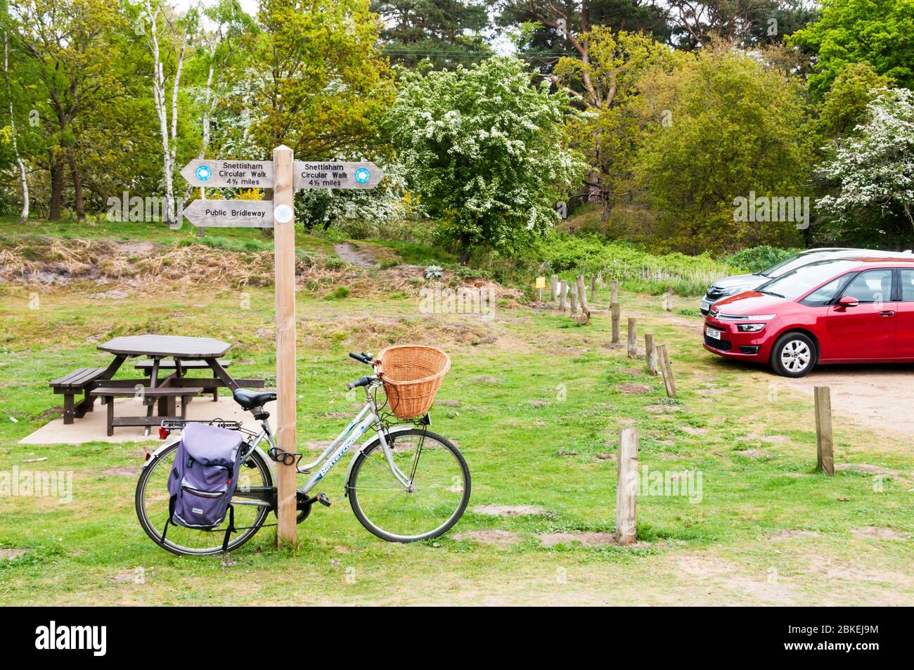Vélo en penchant contre un pont public et une signalisation circulaire de promenade au parking pour Snettisham Common, Norfolk. Banque D'Images