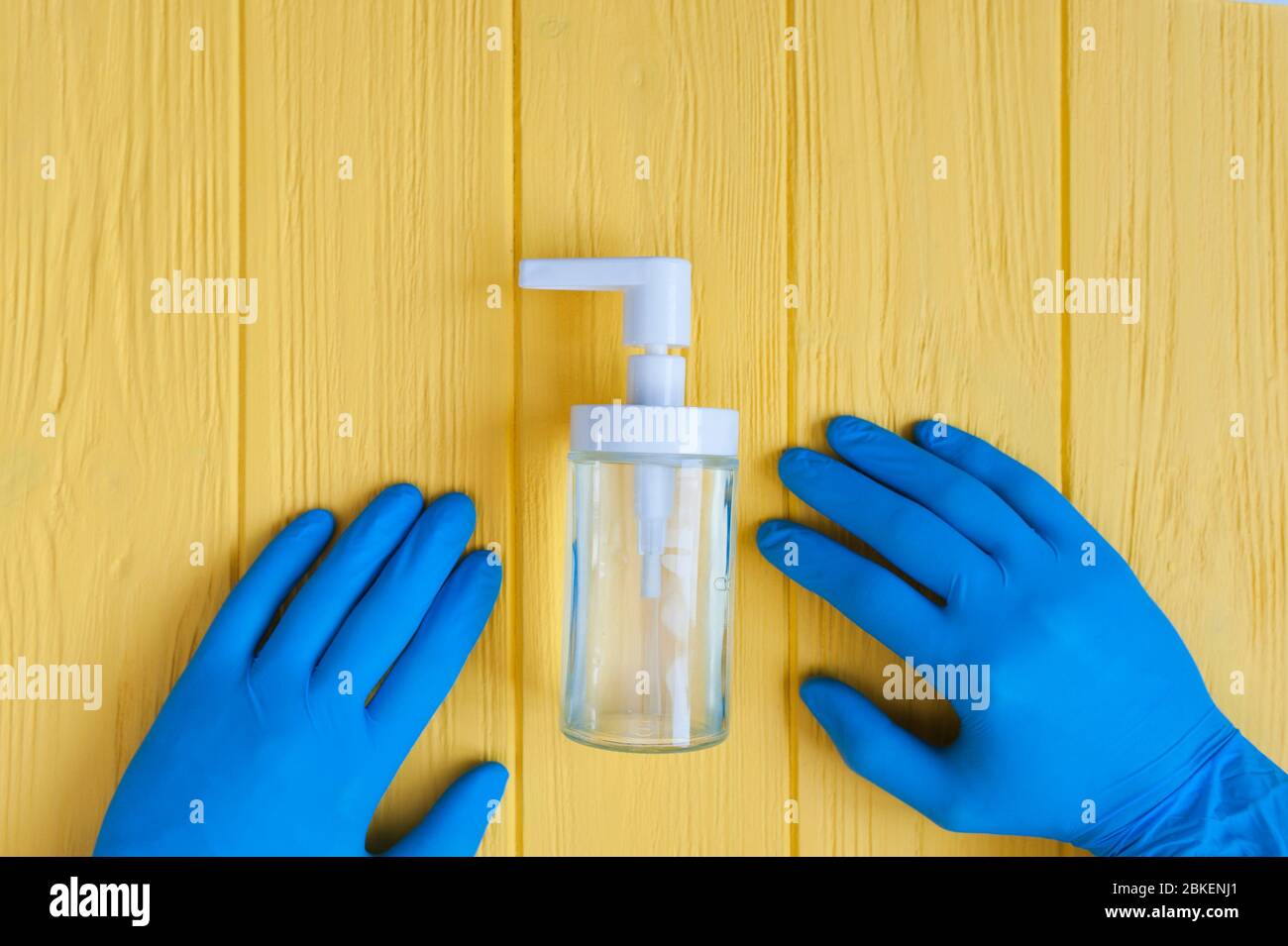Flacon de désinfectant pour les mains et gants bleus rapprochés. Demandez la désinfection des mains. Arrêter le concept du coronavirus. Utilisation de gel antibactérien pour les mains pendant Banque D'Images