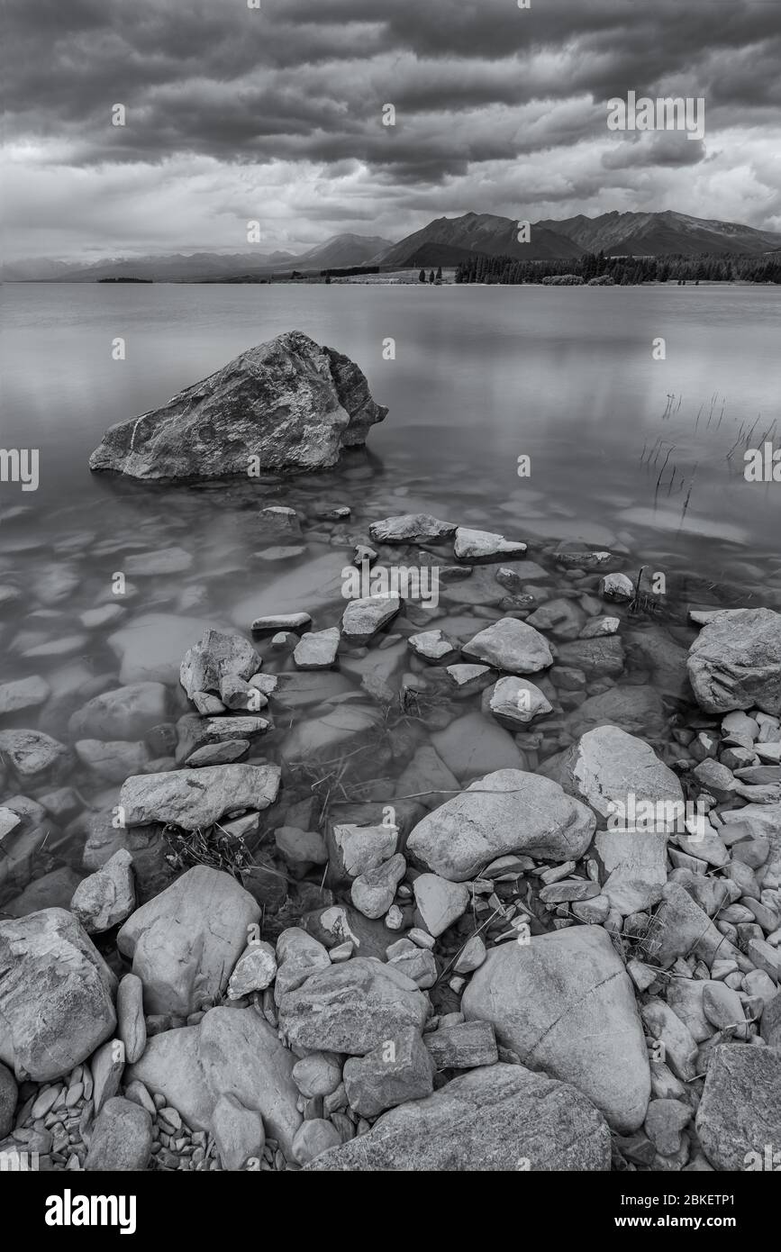 Lac Tekapo, Nouvelle-Zélande - 8 janvier 2020 : exposition longue du lac Tekapo en fin d'après-midi nuageux en noir et blanc Banque D'Images