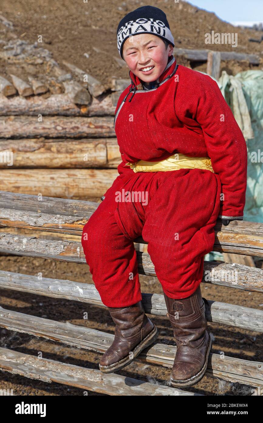 RENCHINLKHUMBE, MONGOLIE, 4 mars 2020 : enfant mongol en robe traditionnelle sur une clôture de camp d'hiver. Banque D'Images