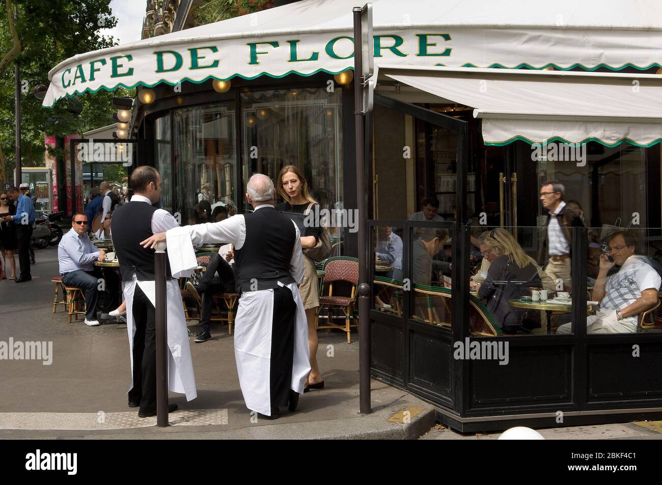 Les serveurs parlent à une jeune femme et à des personnes assis à l'extérieur du café de flore, boulevard St Germain, Paris, France Banque D'Images