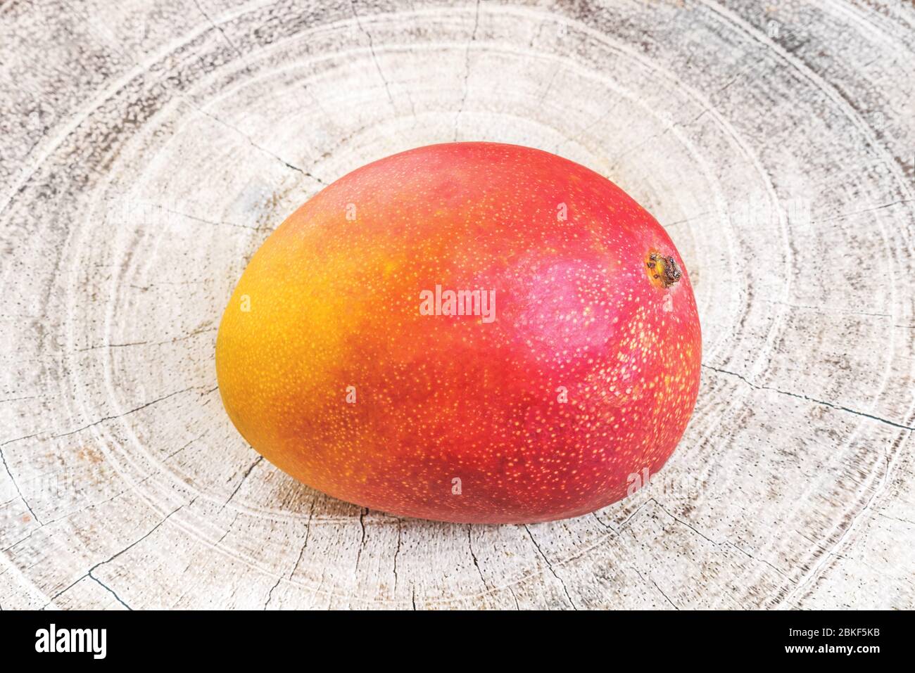 Fruit de mangue tropicale mûre de taille unique sur un fond en bois. Banque D'Images