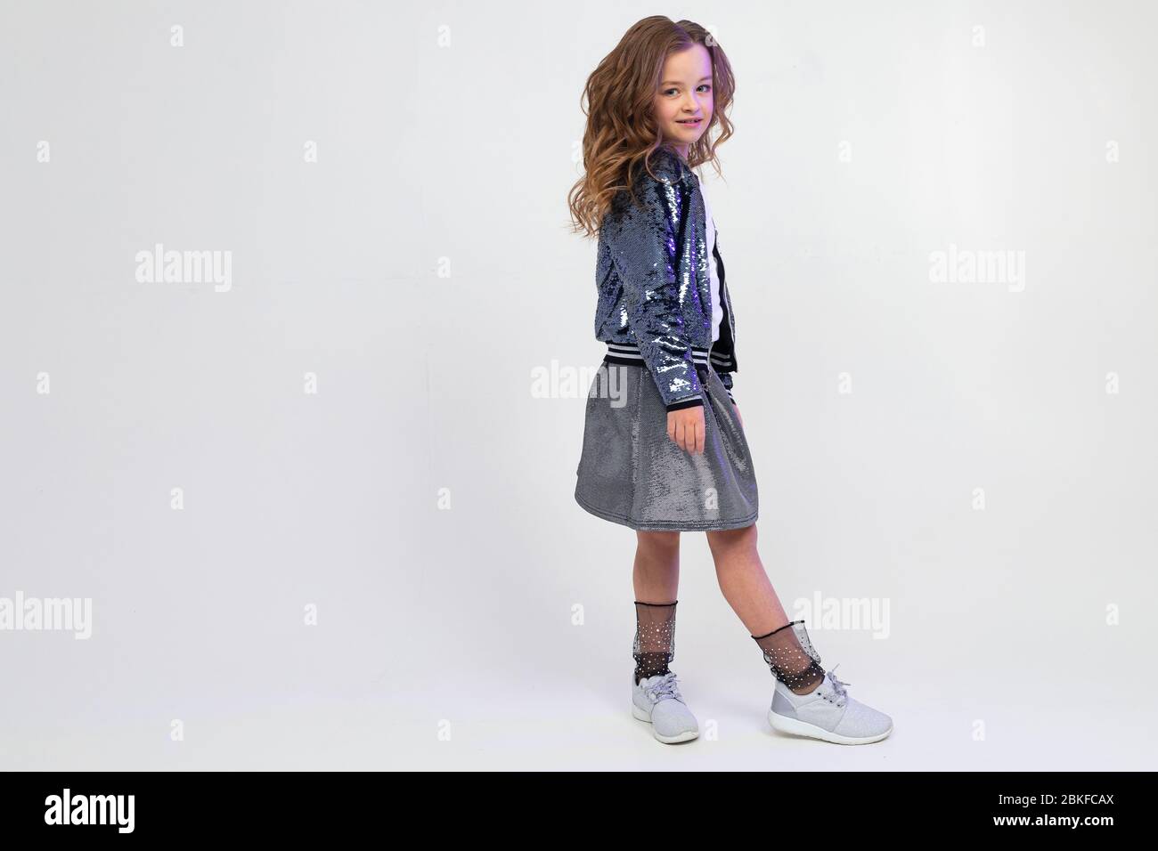 photo pleine longueur d'une fille attrayante dans une image de fête avec une jupe posant latéralement sur un studio blanc de fond avec espace de copie. Banque D'Images