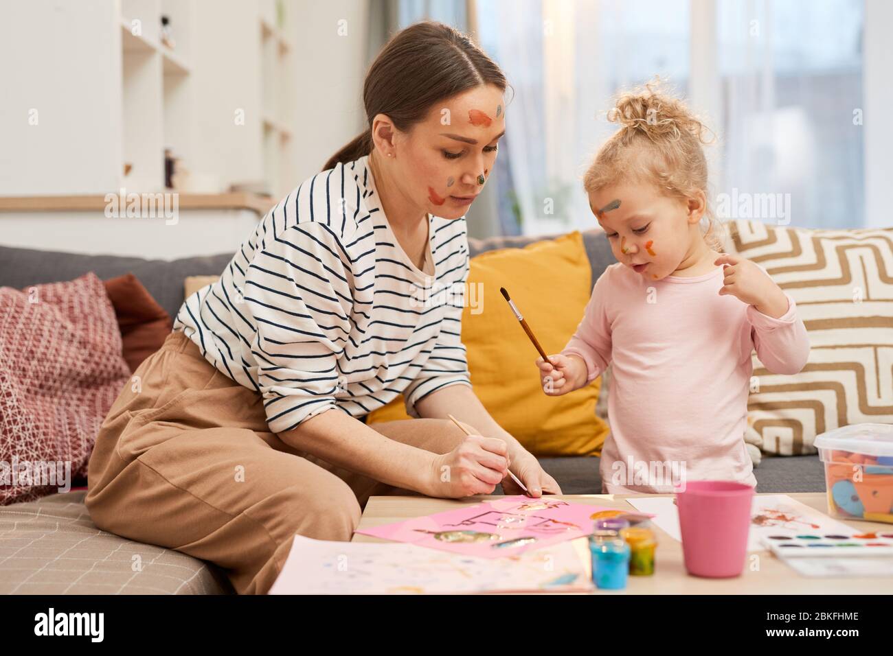 Belle jeune femme passer du temps libre avec sa petite fille peindre des images colorées ensemble Banque D'Images