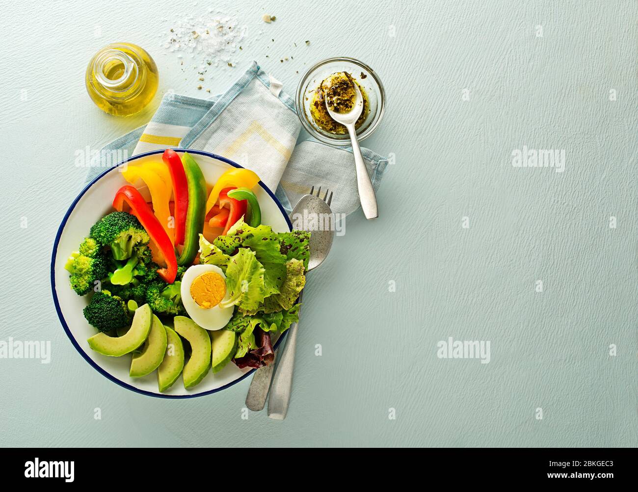 Repas de salade sain avec légumes frais mélangés, avocat et œuf sur fond bleu vue du dessus. Alimentation et santé. Concept de repas sain Banque D'Images