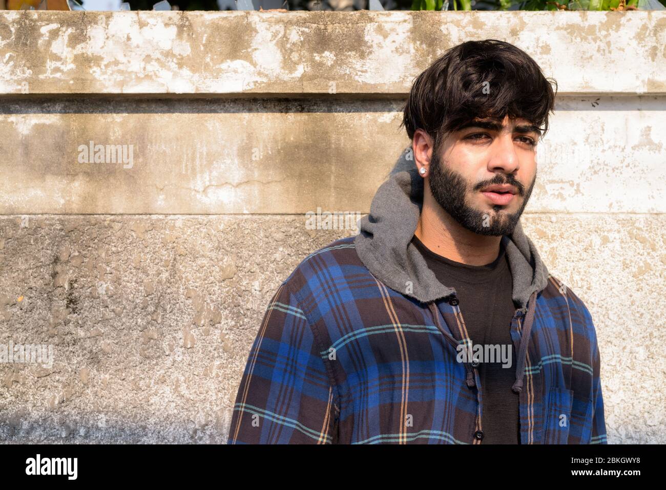 Jeune homme hippster indien barbu pensant dans les rues Banque D'Images
