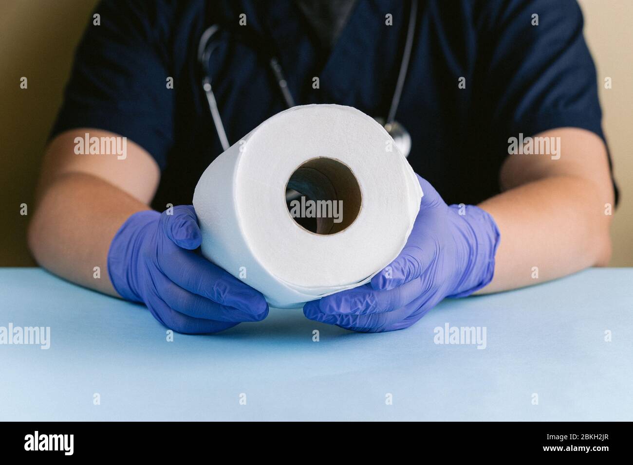 Un professionnel de la santé avec des mains gantées tenant un rouleau de papier toilette Banque D'Images