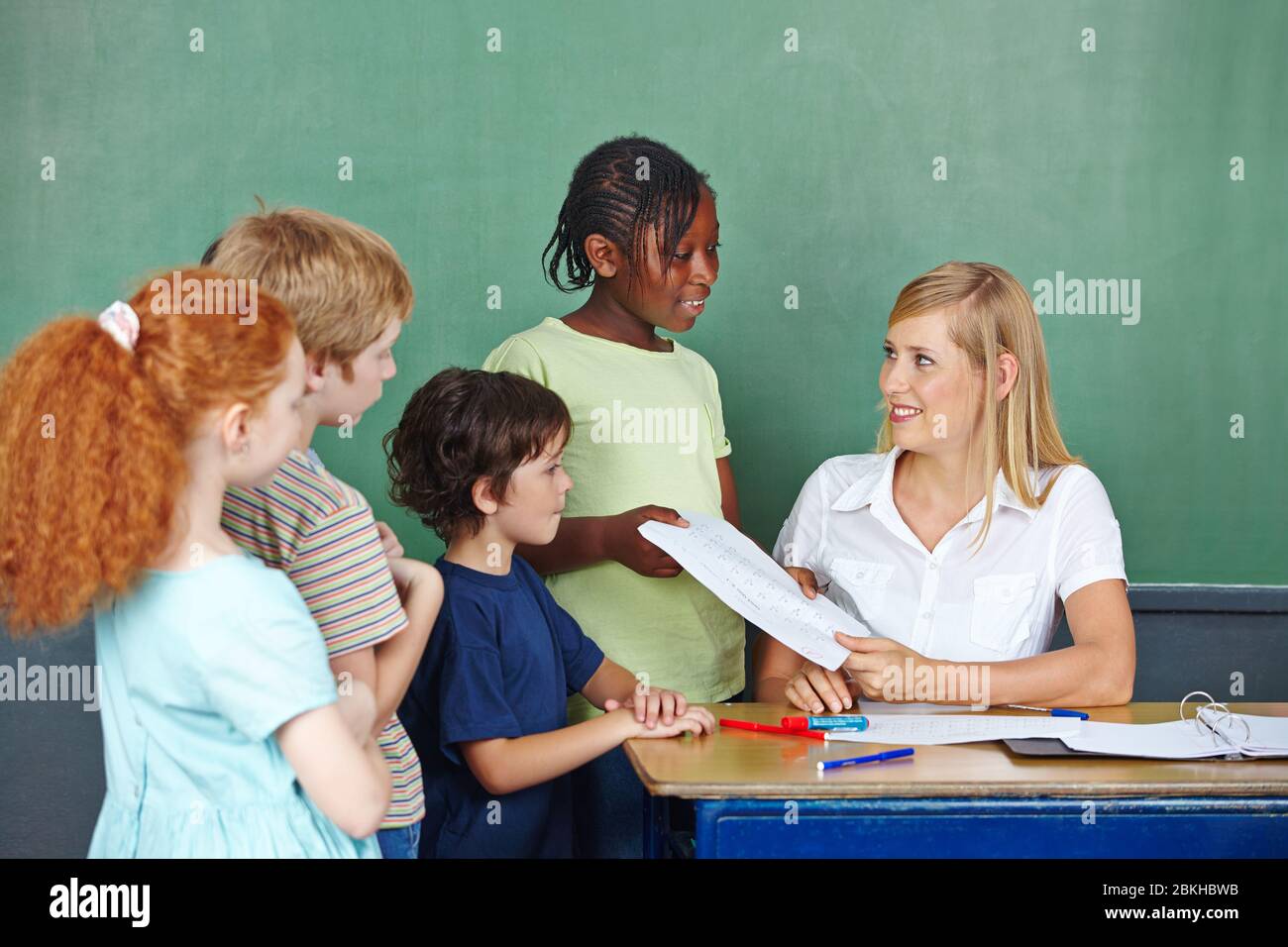 Le professeur donne du travail de classe aux élèves de retour à l'école Banque D'Images